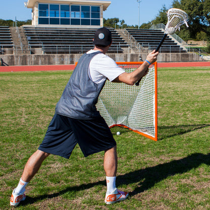 View of male lacrosse player shooting at the Official size 4x4 box lacrosse goal featuring a heavy-duty orange steel frame and white 5mm braided polyethylene net.
