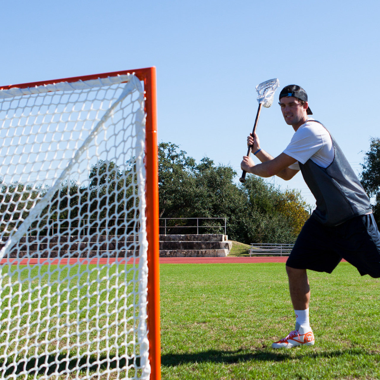 Lacrosse player shooting on the Official size 4x4 box lacrosse goal featuring a heavy-duty orange steel frame and white 5mm braided polyethylene net.
