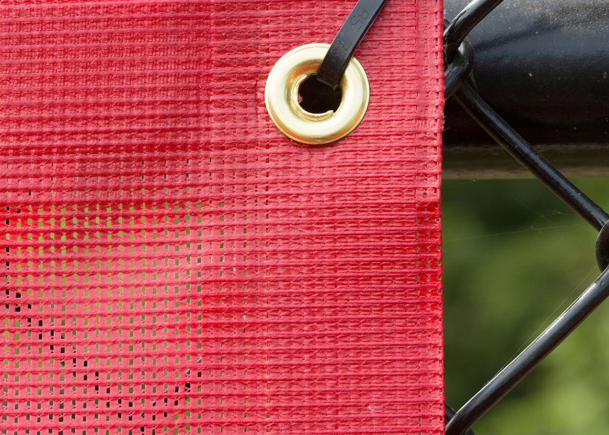 Fencemate windscreen - Red mesh screen with a gold grommet and black metal frame.