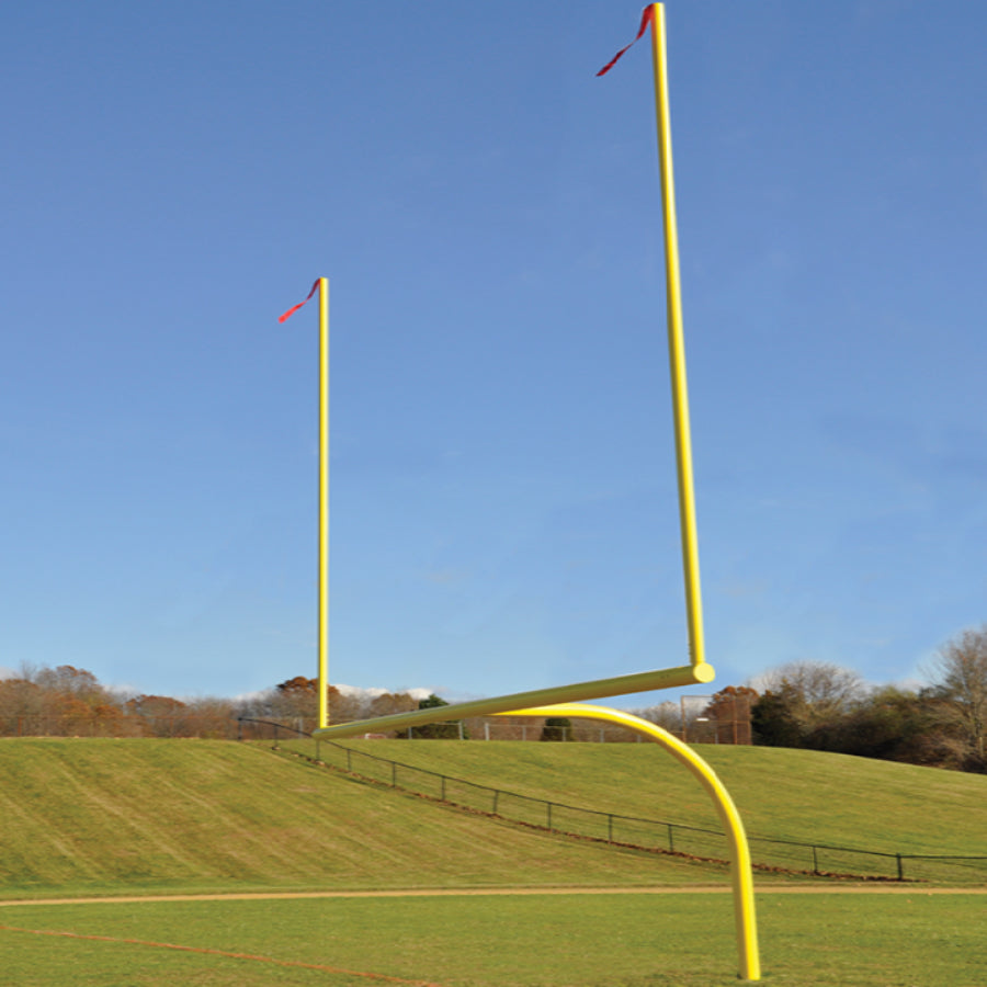Yellow football goal post on a grassy field with a clear blue sky.