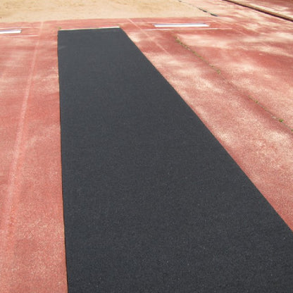 Portable roll-out track runway surface laid out on a practice field, providing a durable and protective rubber lane for triple jump and track events. Laid out on a clay surface field for practice.