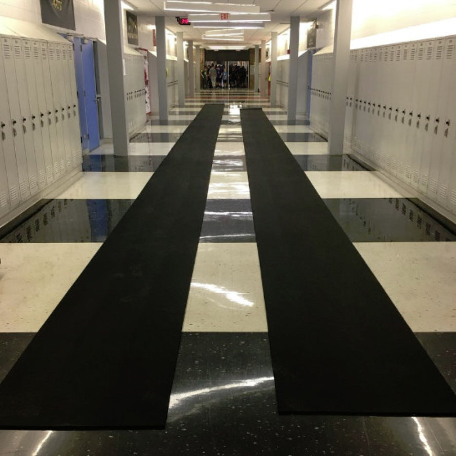 Portable roll-out track runway surface laid out on a practice field, providing a durable and protective rubber lane for triple jump and track events.  2 rolls laid out in the hallway of a high school for indoor off season training.