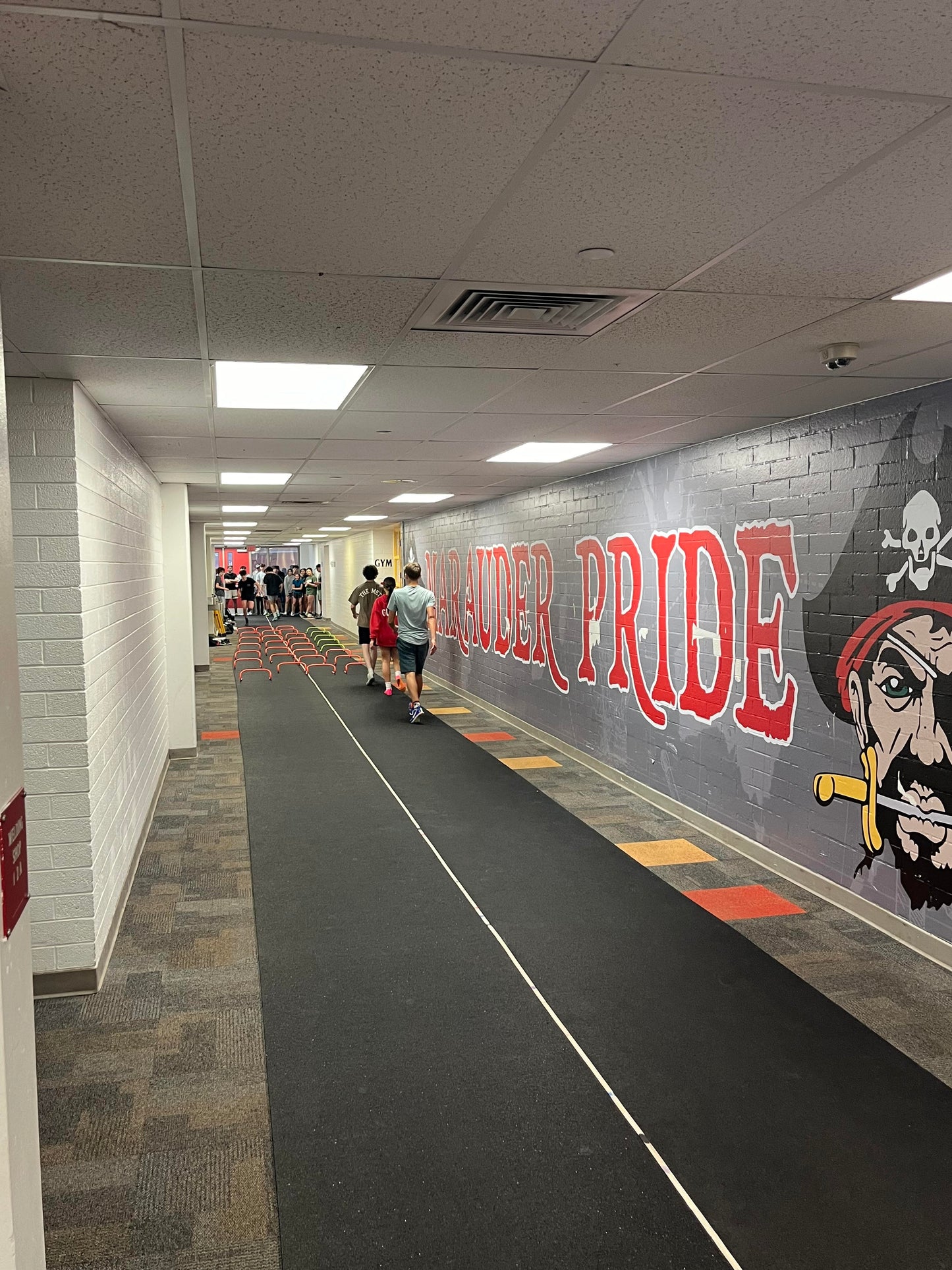 A full length of the Morley Athletic roll-out rubber runway, sold by the linear foot to provide customized lengths for school track and field programs.  Being used inside of a school hallway.