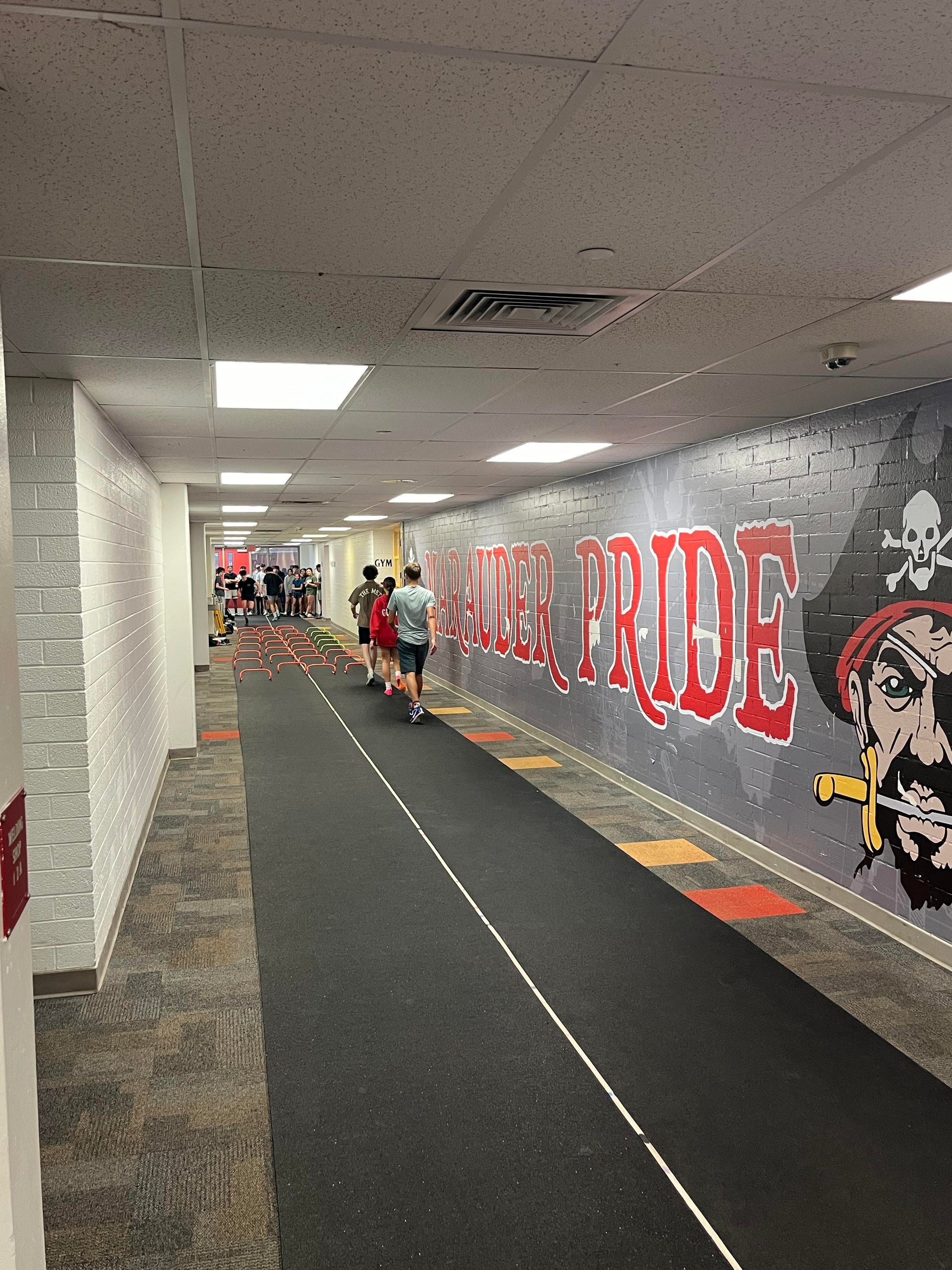 A full length of the Morley Athletic roll-out rubber runway, sold by the linear foot to provide customized lengths for school track and field programs.  Being used inside of a school hallway.