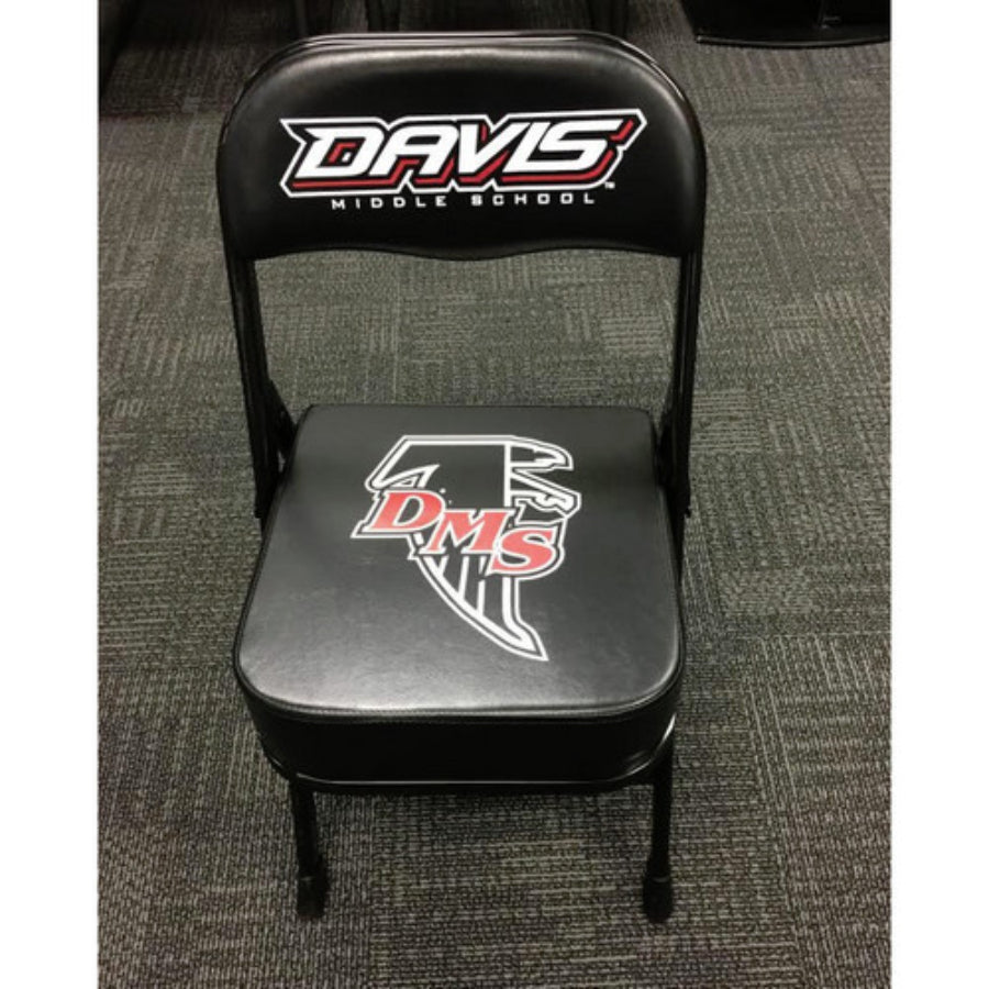 A black deluxe custom sideline chair with a logo on the back, featuring a thick quality cushion and a powder-coated frame, placed on a carpeted floor.